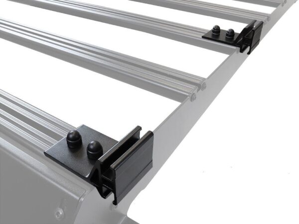 Silver car roof rack crossbars with black mounting clamps viewed from an angle on a white background, showing the end brackets and fasteners.